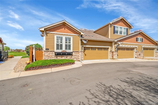 craftsman-style home with board and batten siding, an attached garage, driveway, and stone siding