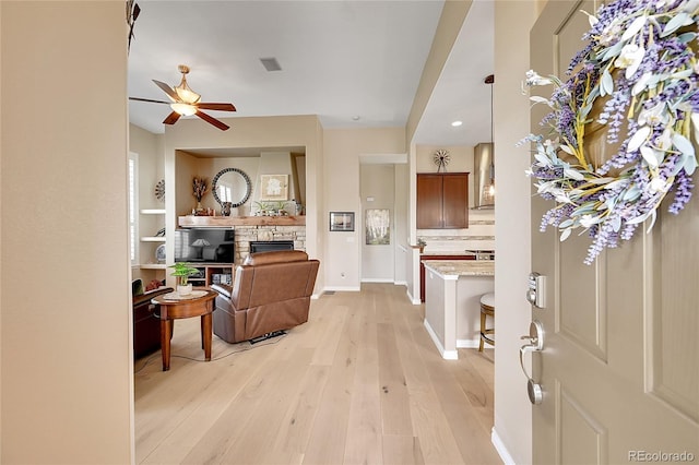 entrance foyer featuring ceiling fan, a stone fireplace, visible vents, light wood-type flooring, and recessed lighting