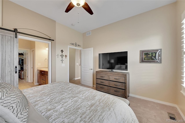 bedroom with baseboards, light carpet, a walk in closet, and visible vents