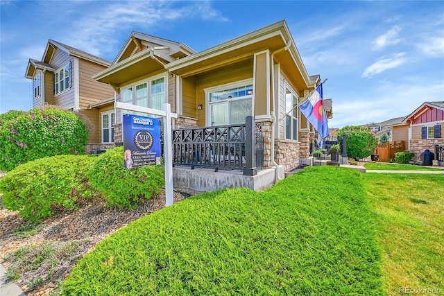 exterior space featuring a lawn, covered porch, and stone siding