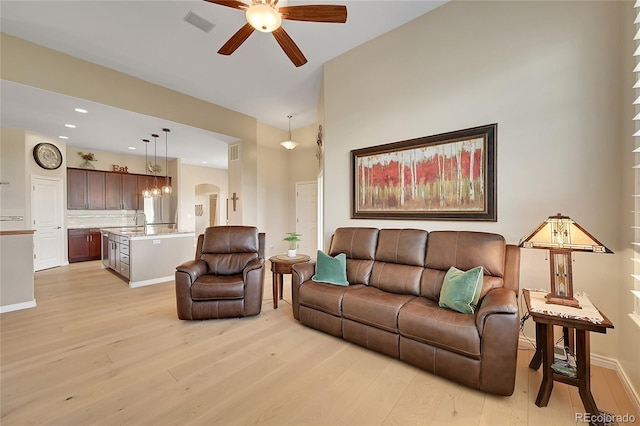 living area with a ceiling fan, arched walkways, baseboards, light wood finished floors, and recessed lighting