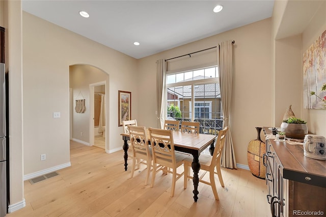 dining space featuring light wood finished floors, arched walkways, recessed lighting, baseboards, and visible vents