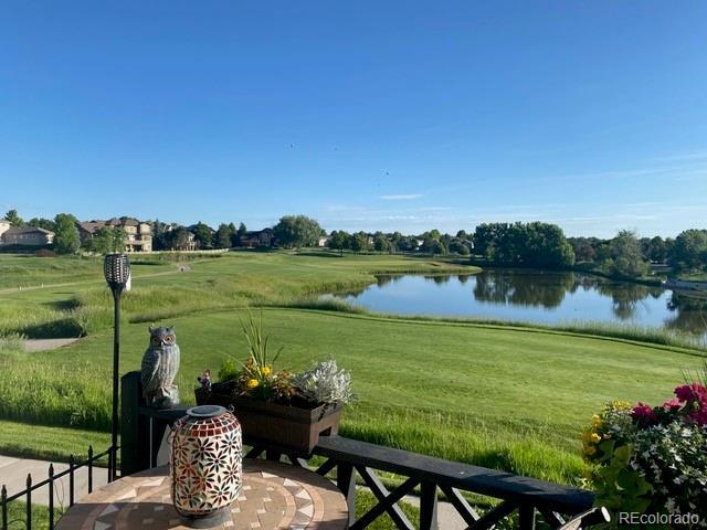 surrounding community featuring a lawn, a water view, and fence