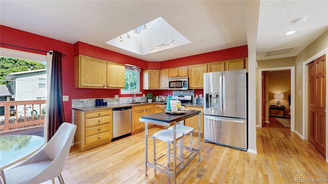 6631 Welch Ct, Arvada, CO 80004 - kitchen with appliances with stainless steel finishes, a sink, light wood finished floors, and baseboards
