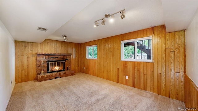6631 Welch Ct, Arvada, CO 80004 - unfurnished living room with wooden walls, carpet flooring, a fireplace, and track lighting