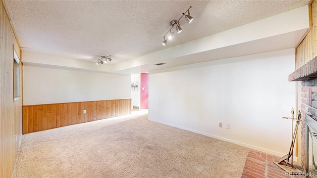 6631 Welch Ct, Arvada, CO 80004 - unfurnished room featuring a brick fireplace, wooden walls, carpet flooring, a textured ceiling, and rail lighting