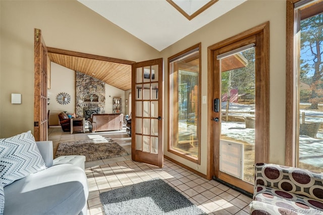 entryway with a fireplace, french doors, light tile patterned floors, and vaulted ceiling