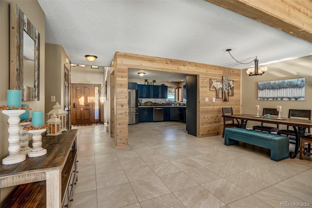 interior space featuring a notable chandelier, light tile patterned floors, a textured ceiling, and wooden walls