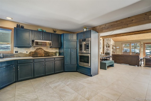 kitchen featuring blue cabinetry, sink, beamed ceiling, light tile patterned floors, and appliances with stainless steel finishes