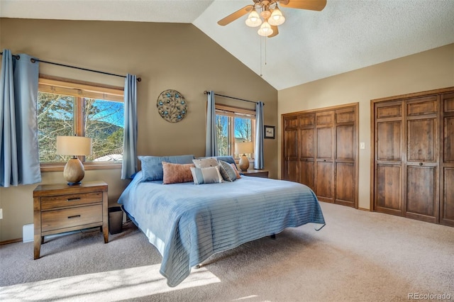 carpeted bedroom featuring ceiling fan, two closets, and vaulted ceiling