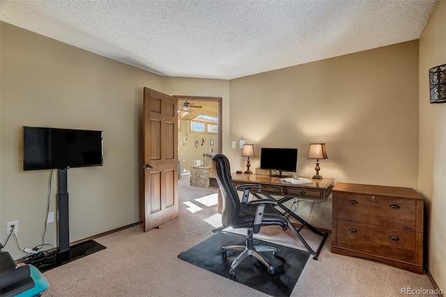 home office featuring a textured ceiling, ceiling fan, and light carpet