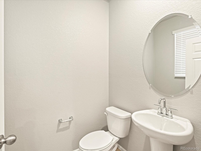 bathroom featuring baseboards, a sink, and toilet