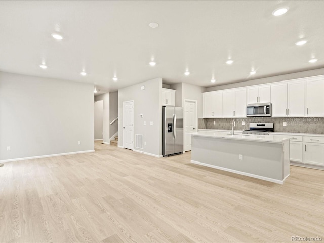 kitchen featuring tasteful backsplash, light wood-type flooring, light countertops, white cabinetry, and stainless steel appliances