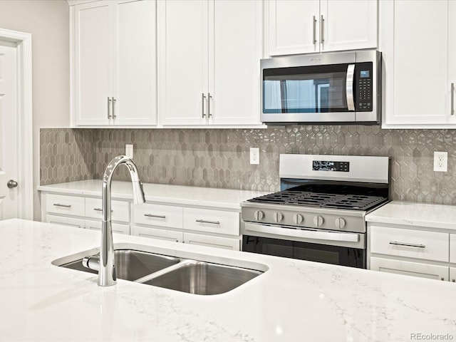 kitchen with a sink, tasteful backsplash, white cabinets, and stainless steel appliances