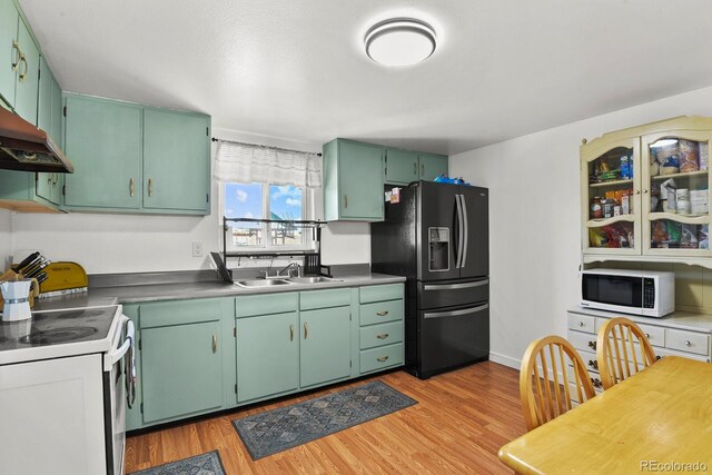 kitchen with green cabinetry, sink, light hardwood / wood-style floors, and white appliances