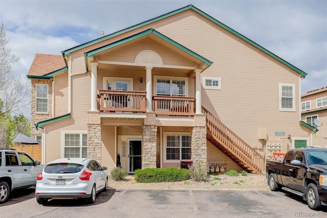 3993 S Dillon Way Unit 104, Aurora, CO 80014 - view of front facade featuring stone siding, a balcony, uncovered parking, and stairs