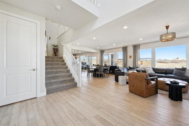 living area featuring light wood finished floors, stairs, a notable chandelier, and recessed lighting