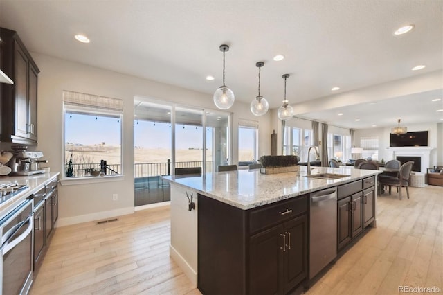 kitchen with a center island with sink, visible vents, appliances with stainless steel finishes, light wood-style floors, and a sink