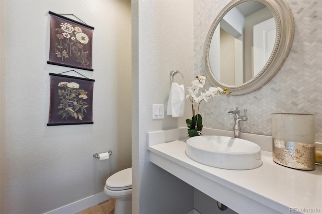 half bathroom with toilet, baseboards, and a sink