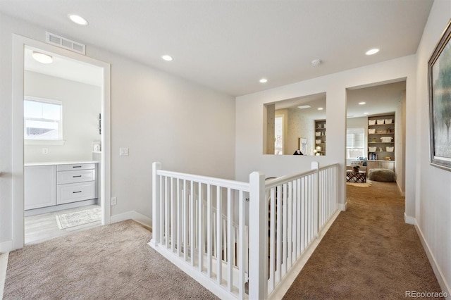 corridor with visible vents, baseboards, carpet, an upstairs landing, and recessed lighting