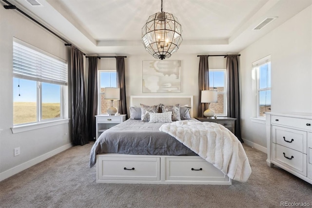 carpeted bedroom featuring an inviting chandelier, visible vents, a tray ceiling, and baseboards