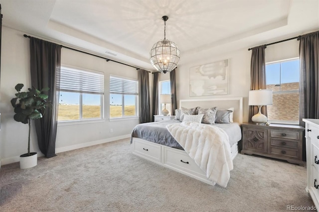 bedroom featuring light carpet, baseboards, visible vents, a tray ceiling, and a notable chandelier