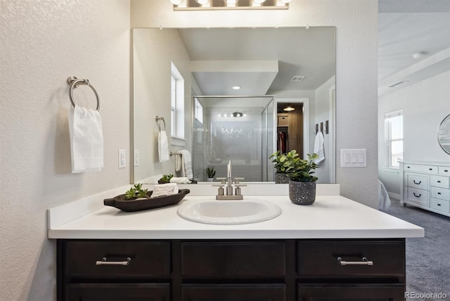 full bath featuring a stall shower, visible vents, a textured wall, and vanity