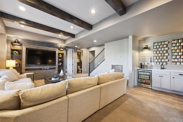 living room with wine cooler, stairway, wet bar, light wood-type flooring, and beamed ceiling