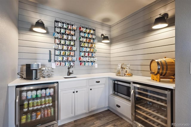 bar featuring wet bar, beverage cooler, stainless steel microwave, and dark wood-style flooring