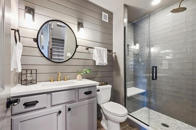 bathroom with wooden walls, a stall shower, vanity, and toilet