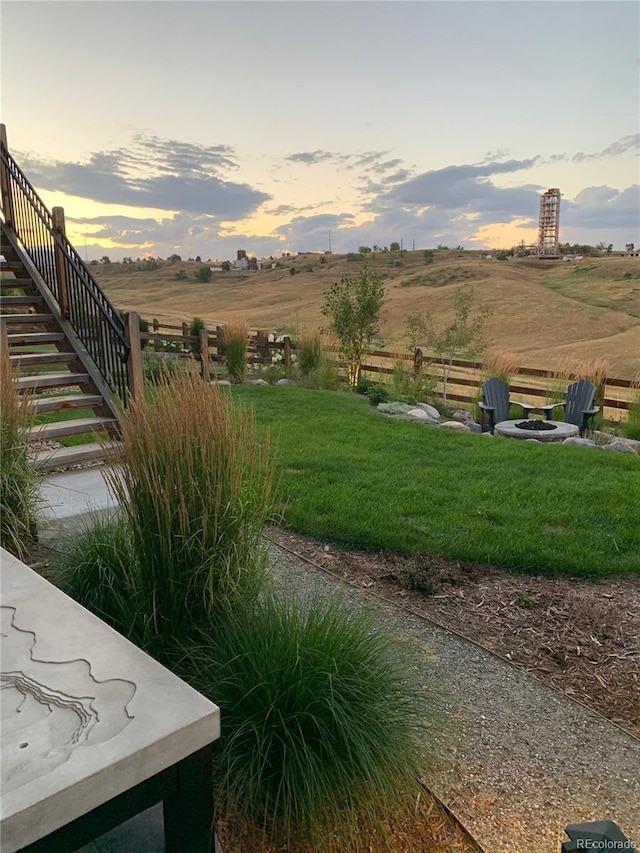 view of yard featuring fence, a fire pit, and a rural view