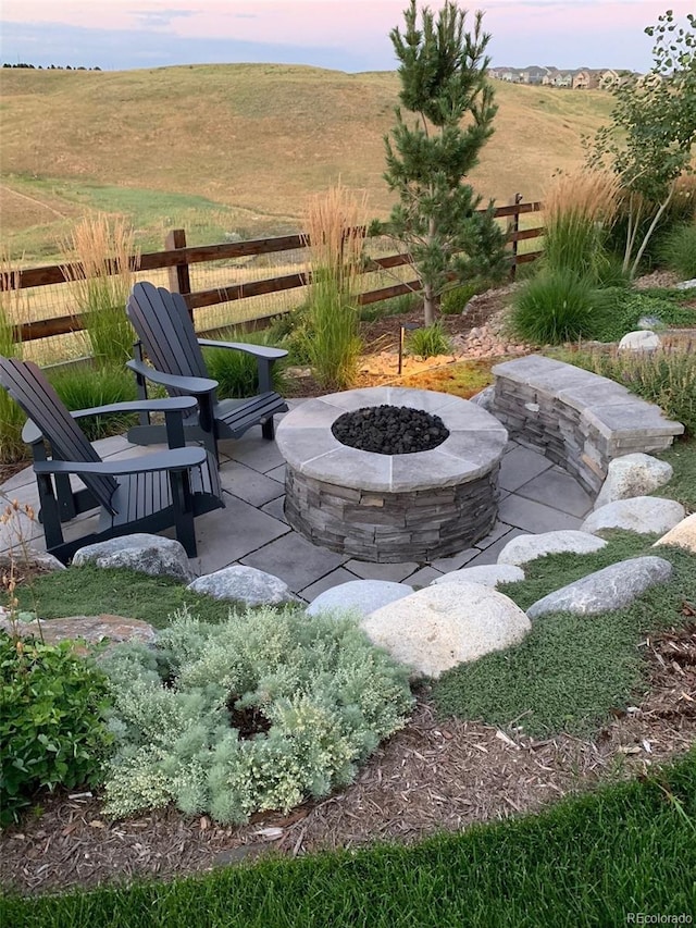 view of patio / terrace with an outdoor fire pit, a rural view, and fence