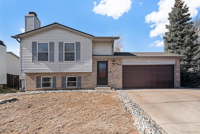 split level home with brick siding, driveway, a chimney, and an attached garage