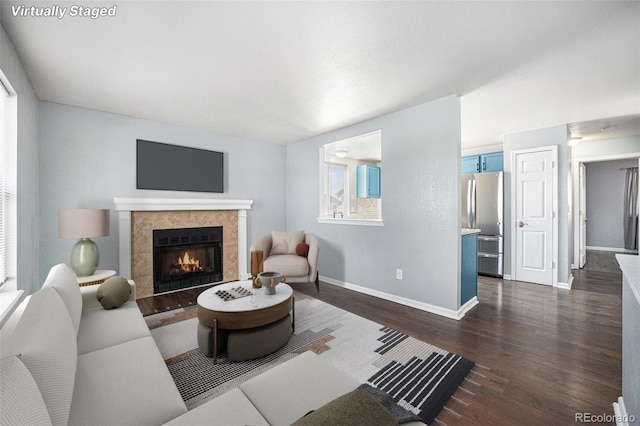 living room with baseboards, dark wood-type flooring, and a tile fireplace