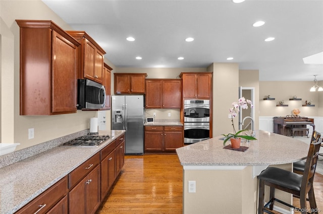 16685 E 101st Ave, Commerce City, CO 80022 - kitchen with appliances with stainless steel finishes, a breakfast bar, light wood-style floors, a kitchen island with sink, and recessed lighting