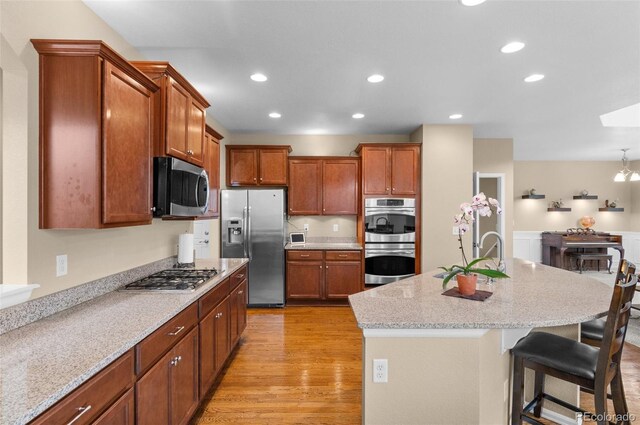 16685 E 101st Ave, Commerce City, CO 80022 - kitchen with appliances with stainless steel finishes, a breakfast bar, light wood-style floors, a kitchen island with sink, and recessed lighting