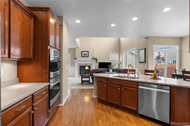 16685 E 101st Ave, Commerce City, CO 80022 - kitchen featuring a glass covered fireplace, recessed lighting, light stone counters, a sink, and appliances with stainless steel finishes