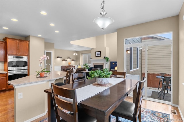 16685 E 101st Ave, Commerce City, CO 80022 - dining area featuring visible vents, a fireplace, light wood-type flooring, baseboards, and recessed lighting