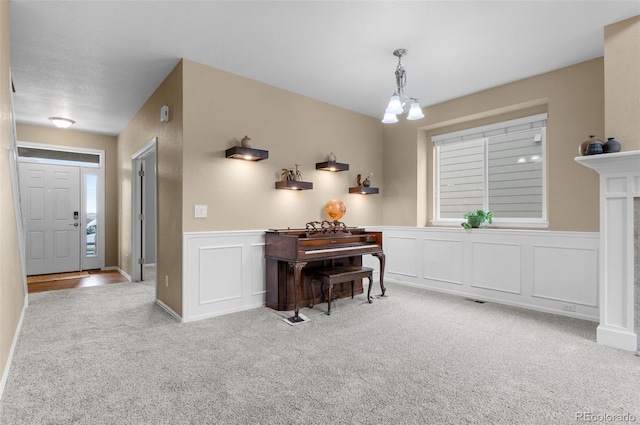 16685 E 101st Ave, Commerce City, CO 80022 - living area featuring a notable chandelier, a fireplace, carpet floors, a decorative wall, and a wainscoted wall