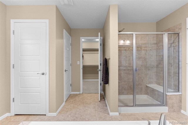16685 E 101st Ave, Commerce City, CO 80022 - bathroom with baseboards, a walk in closet, tile patterned floors, and a stall shower