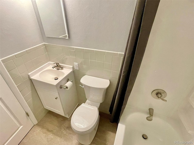 9600 W 18th Dr Unit 9610, Lakewood, CO 80215 - bathroom featuring vanity, tile walls, a wainscoted wall, a textured wall, and bathtub / shower combination