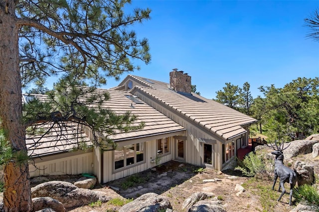 2611 Fox Acres Dr E, Red Feather Lakes, CO 80545 - back of house with board and batten siding, a tiled roof, and a chimney