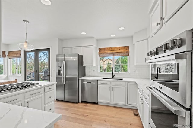 9432 La Quinta Way, Lone Tree, CO 80124 - kitchen with stainless steel appliances, a sink, white cabinetry, light stone counters, and recessed lighting