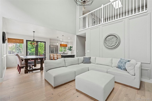 9432 La Quinta Way, Lone Tree, CO 80124 - living room featuring light wood-style floors, baseboards, a chandelier, and a high ceiling
