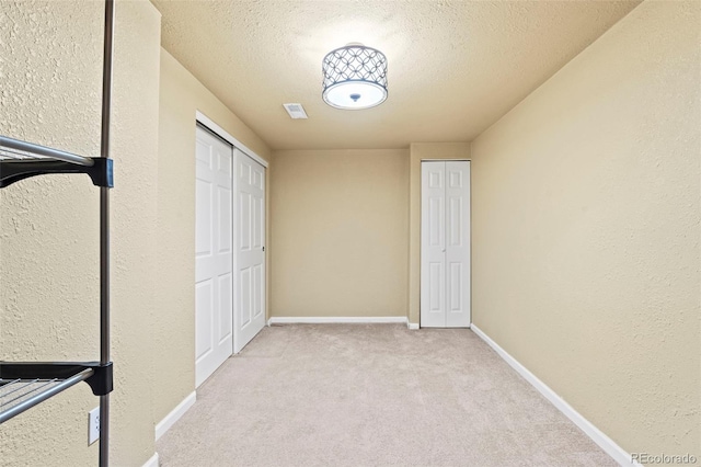 9432 La Quinta Way, Lone Tree, CO 80124 - unfurnished bedroom featuring two closets, carpet floors, a textured ceiling, baseboards, and a textured wall