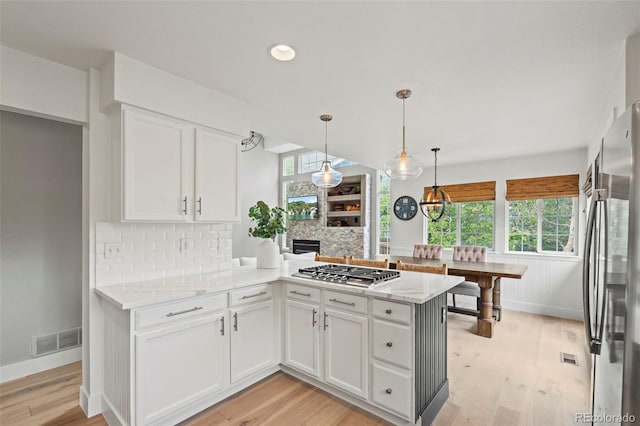 9432 La Quinta Way, Lone Tree, CO 80124 - kitchen featuring appliances with stainless steel finishes, white cabinetry, backsplash, light wood-type flooring, and a fireplace