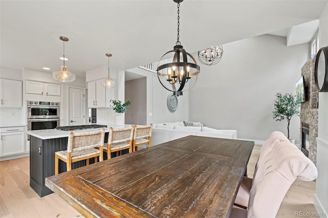 9432 La Quinta Way, Lone Tree, CO 80124 - dining space with light wood-style flooring, a chandelier, a stone fireplace, and recessed lighting
