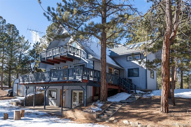 snow covered back of property with a wooden deck