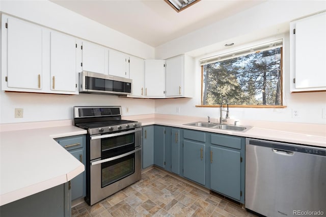 kitchen featuring white cabinets, blue cabinetry, sink, and appliances with stainless steel finishes