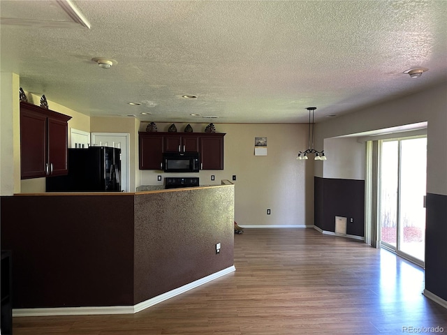 kitchen featuring pendant lighting, light wood-type flooring, black appliances, a textured ceiling, and dark brown cabinets